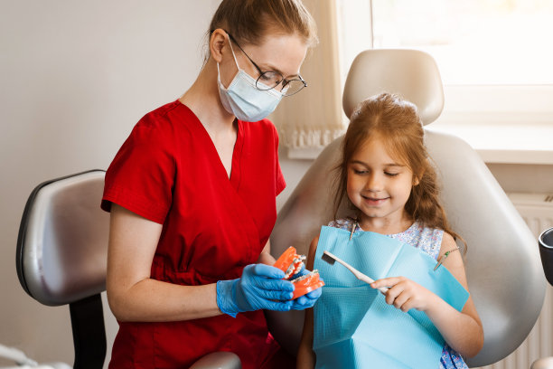 儿科牙医为牙科儿童教授口腔卫生课。牙医教孩子如何正确使用牙刷刷牙。颌解剖模型刷牙。图片下载