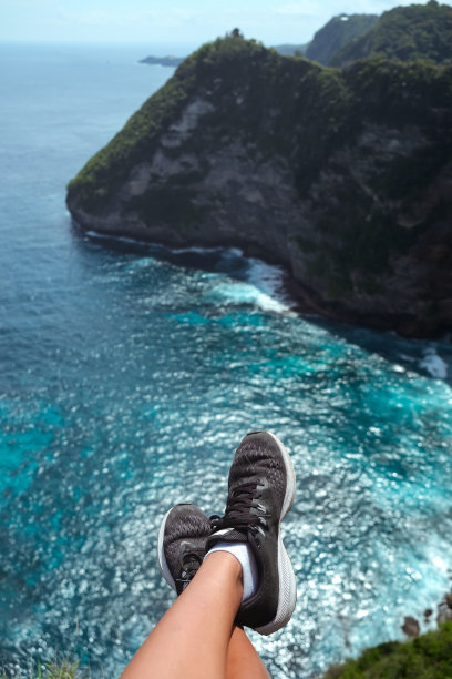 在蓝绿色的海面上，穿着鞋子的脚被吊着图片下载