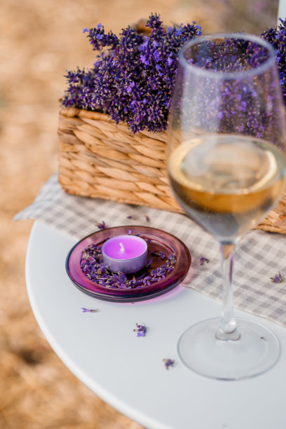 一杯白葡萄酒和一瓶在普罗旺斯的薰衣草地里。背景是紫罗兰花图片下载