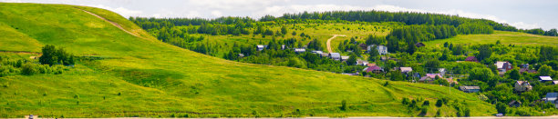 风景的绿色草地在山坡上与蓝天的背景。自然风光秀丽的乡村有山有村图片下载