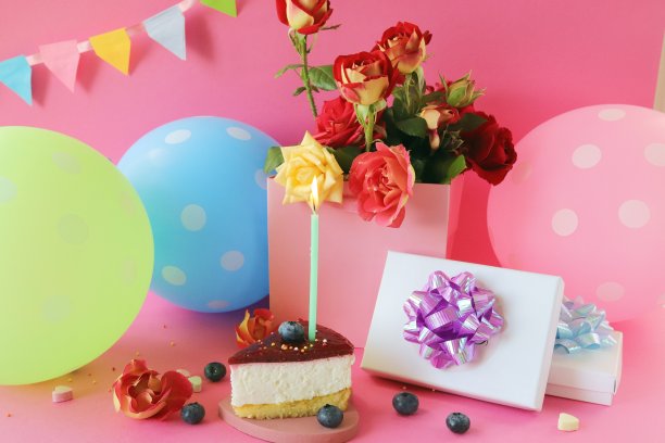 一块浆果蛋糕，点燃一支蜡烛，一束新鲜的玫瑰，礼物，气球和节日旗帜在明亮的背景，生日快乐图片下载
