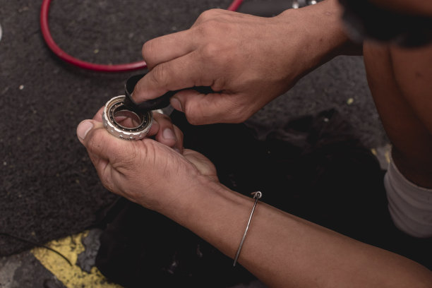 维修人员用一小块布清洗底部支架的轴承。自行车修理店的维修服务。图片下载