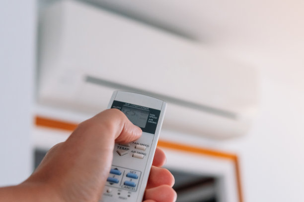 一个人的手在热浪中打开空调的遥控器。图片下载