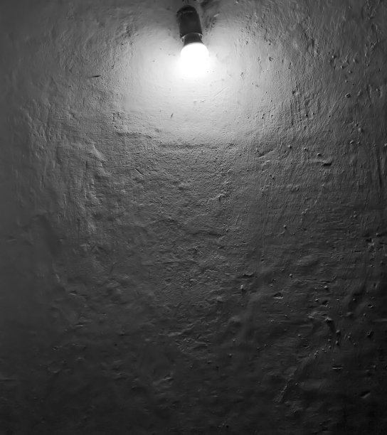 白色墙壁上的灯泡，表面凹凸不平。黑白照片与背景文字图片下载