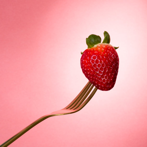 单瓣草莓叶，黄铜金叉，粉红色背景。食品摄影。社论。图片下载