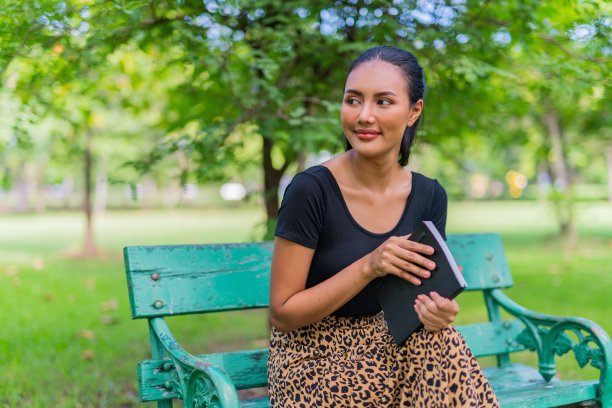 一个美丽和好看的年轻亚洲女性模特女士与一本书在公园图片下载