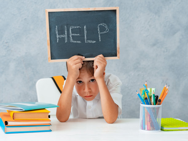伤心累沮丧的男生男生在桌子上拿着纸和单词帮助。学习困难，教育观念图片下载