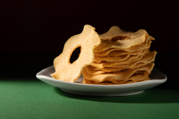 苹果干放在白色盘子里。深色背景的照相馆照片。图片下载