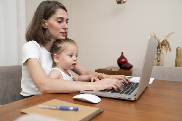 带着小女儿在家工作的女人。图片下载