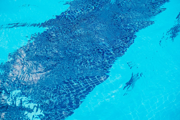 纯蓝的水在游泳池与光反射。水游泳池表面夏季背景图片下载