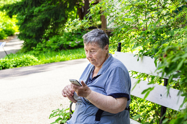 户外照片的女性摆出惊人的背景，坐在长椅上绿色的灌木丛。图片下载