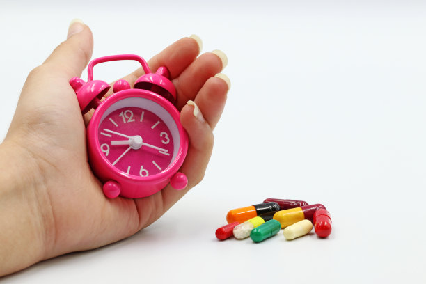 手里拿着闹钟。时间和药物或药丸的概念。图片下载