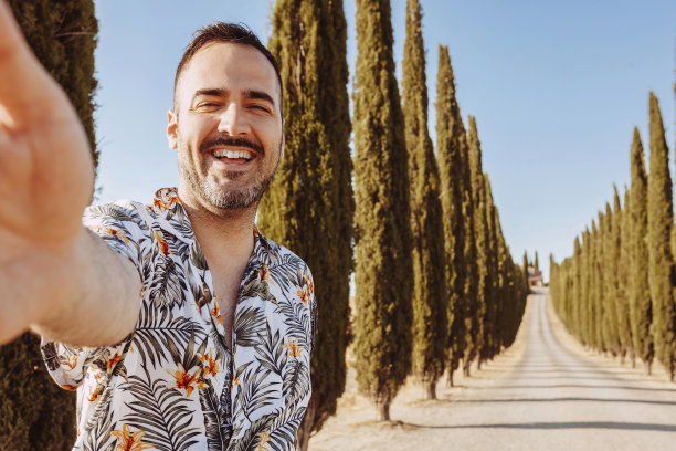 年轻男子在托斯卡纳的柏树前自拍图片下载