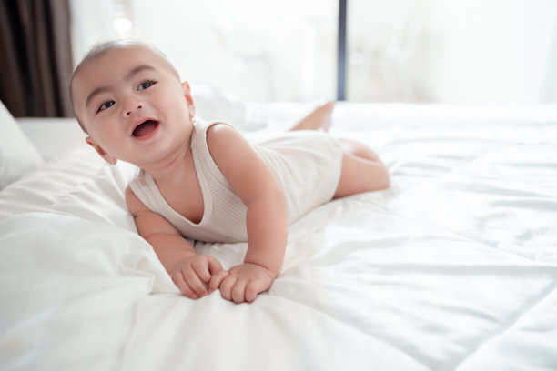 微笑的新生婴儿或可爱的小躺在家里白色的床上。婴儿儿童肖像快乐理念，健康育儿晨。图片下载