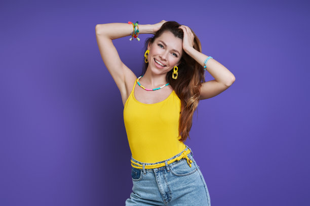 美丽的年轻女子挽着头发微笑着站在紫色的背景图片下载