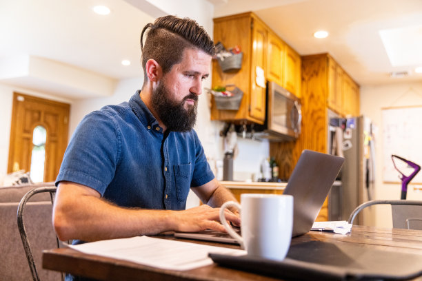 混血男子在家吃饭时工作图片下载