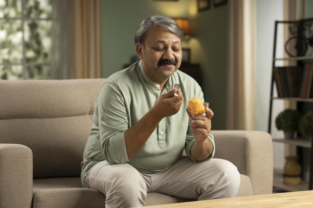 成熟男人坐在沙发上吃冰淇淋的照片图片下载