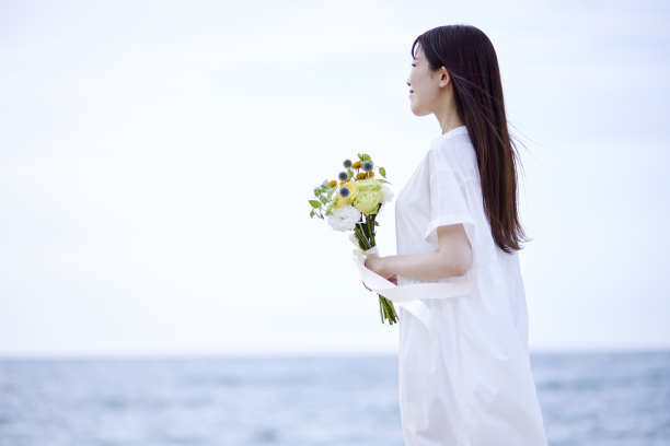 年轻的日本女子穿着裙子，手持花束图片下载