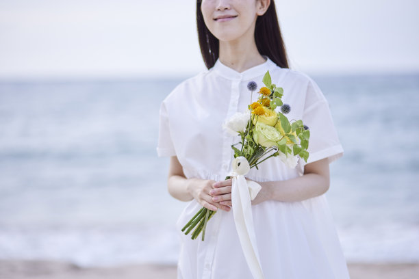 年轻的日本女子穿着裙子，手持花束图片下载