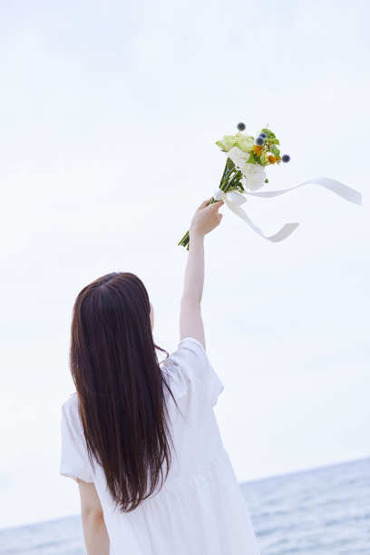 年轻的日本女子穿着裙子，手持花束图片下载
