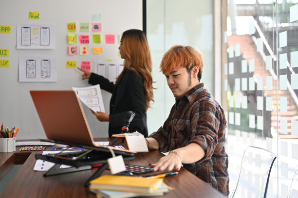 泰国亚洲商业工作者在木制办公桌上的数字小玩意儿的现代办公室里从事媒体设计师的职业。技术和设计理念。图片下载