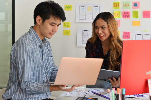 以白板上的信息为背景，办公室职员在笔记本电脑上讨论数据的肖像正面视图。技术和设计理念。图片下载