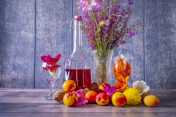 木桌上放着成熟的桃子、一瓶葡萄酒、酒杯和一瓶野花。图片下载