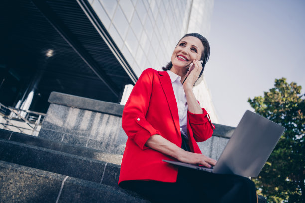 快乐微笑的照片营销老太太坐在现代金融中心使用上网本说话小工具雇主雇员户外图片下载
