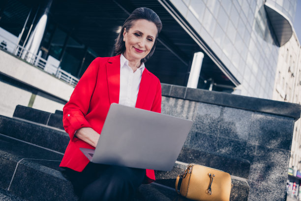 执行时髦老太太坐在楼梯金融现代中心使用上网本在户外发短信的伙伴的照片图片下载