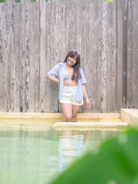 胖乎乎的快乐的年轻亚洲女子穿着泳装在游泳池附近。图片下载