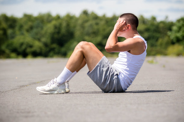 一个19岁的少年在公园里做仰卧起坐图片下载