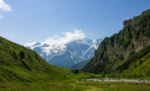绿色的山坡和高山，雪峰覆盖在山谷和高山草地上图片下载