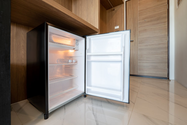 打开木制柜台下的小冰箱，在酒店高级客房门前。图片下载