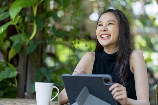 亚洲女性数字游牧民幸福自由快乐微笑工作使用平板电脑在花园户外，亚洲女性自由放松休闲工作任何地方工作和旅游与花园散景背景图片下载