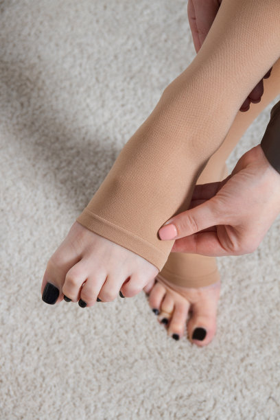 白色房间里的一位女士穿着米色紧身丝袜。女孩在家里穿长袜。漂亮的女腿图片下载