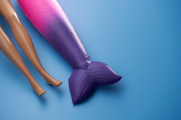 蓝色背景的美人鱼鳍和玩具人腿图片下载