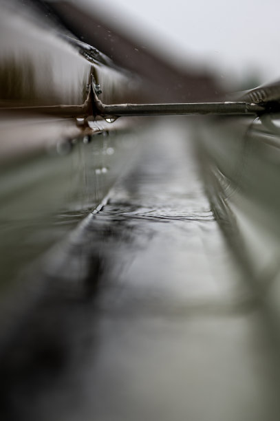 有选择地集中在一段有吊架的住宅排水沟，在暴风雨中输送水。雨点飞溅可见。图片下载