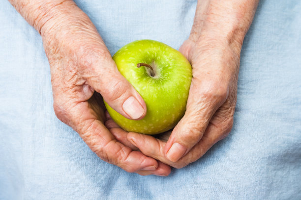 拿着青苹果的老妇人的手。长寿的概念。图片下载