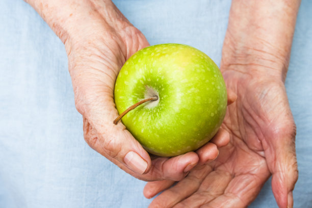 拿着青苹果的老妇人的手。长寿的概念。图片下载