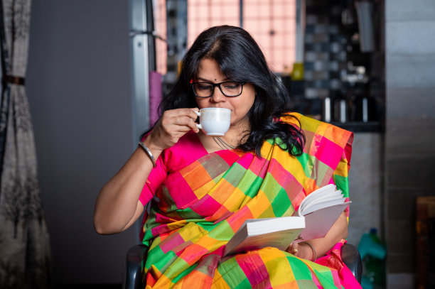 一个女人坐在家里看书、喝茶或喝咖啡的照片。图片下载