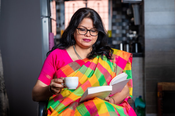 一个女人坐在家里看书、喝茶或喝咖啡的照片。图片下载