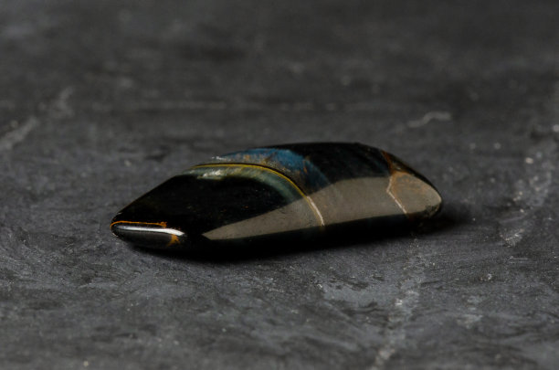 石头是一种矿物质，背景是黑色的混凝土。在占星学和替代或补充医学中使用矿物和水晶的概念。图片下载