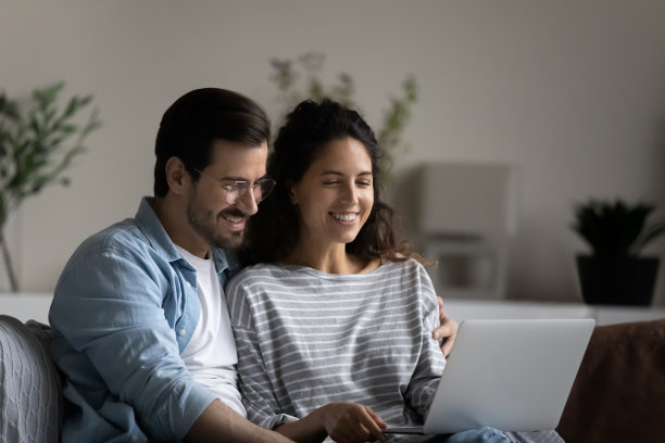 千禧一代夫妇坐在沙发上用笔记本电脑购买服务图片下载