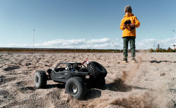 小男孩在户外沙滩上玩遥控车，享受快乐的童年图片下载