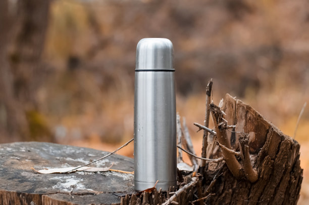 室外真空钢质保温杯。秋天森林里的野营瓶。远足理念，在大自然中放松，在寒冷的天气里喝热饮。图片下载