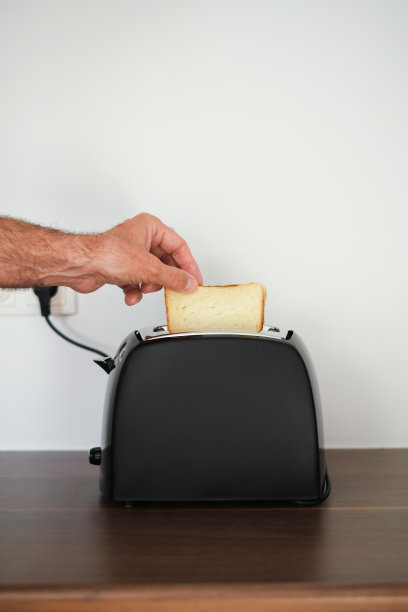 一名男子正在用烤面包机准备早餐的烤面包图片下载