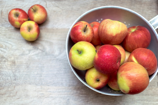 成熟的红苹果在金属碗在木桌上的文本拷贝空间。新鲜水果概念特写，维生素水果背景，横幅图片下载