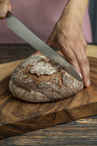 妇女切割新鲜制作的面包-股票的照片图片下载