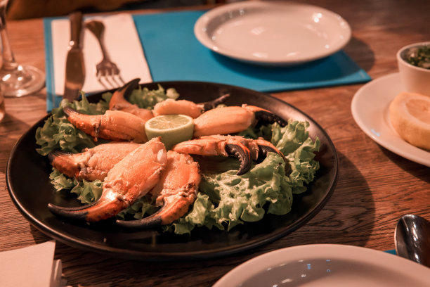 在一家优雅的餐厅里，一盘蟹爪子配生菜和柠檬摆在桌子上图片下载