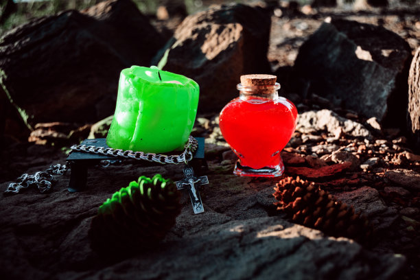 燃烧的绿色蜡烛，月亮的象征，一个护身符躺在一块石头上的黑暗的自然背景。异教徒巫术，斯拉夫传统。巫术，深奥的精神仪式图片下载